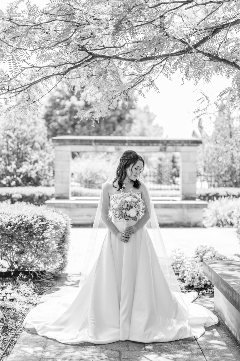 Married bride and groom standing in front of barn looking at each other smiling