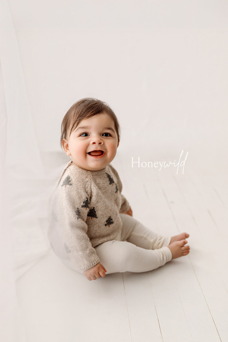 Newborn baby wrapped in soft blue fabric, yawning while wearing a matching knit bonnet. Captured by Honeywild Photo, a Grand Rapids newborn photographer specializing in artistic and timeless baby portraits