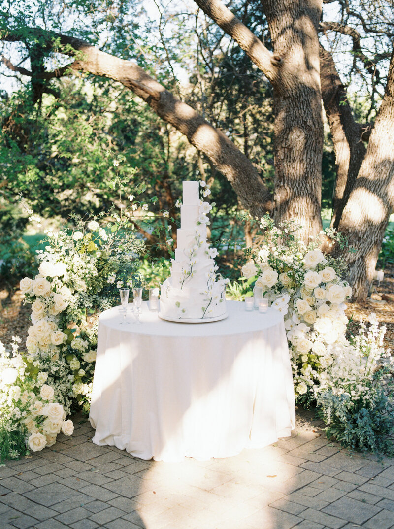Cake table surrounded by meadow of green and white florals