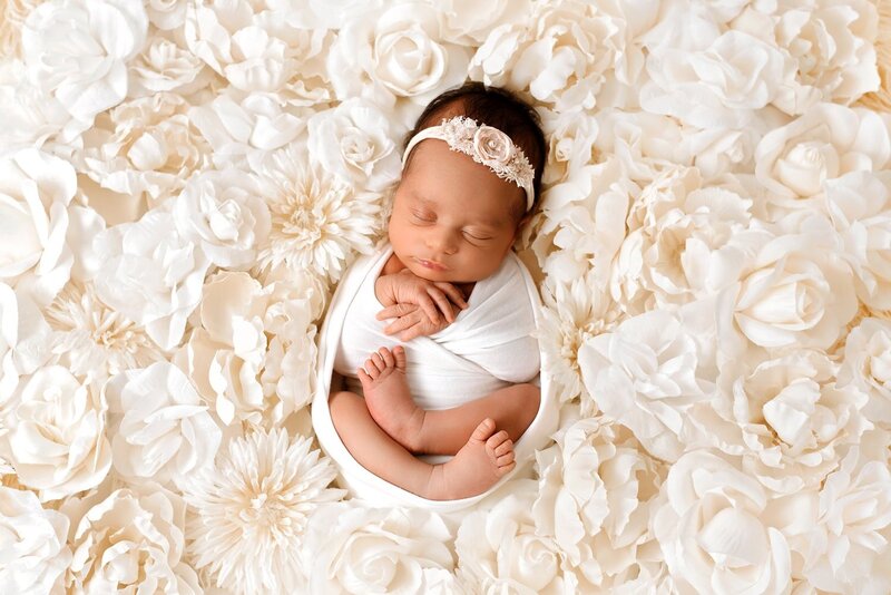 Baby girl wrapped in white in a cream flower nest during an in-home newborn photo session in Burnaby.