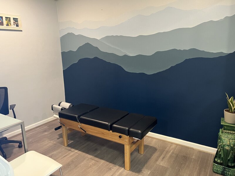 A serene painting, behind a chiropractic adjusting table, built from natural materials.