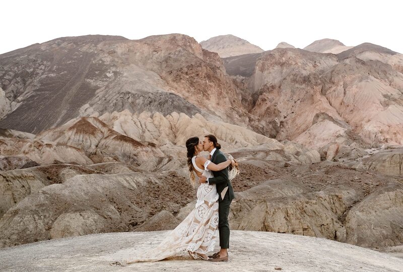 Couple kissing at sunrise with Artist's Palette in background.