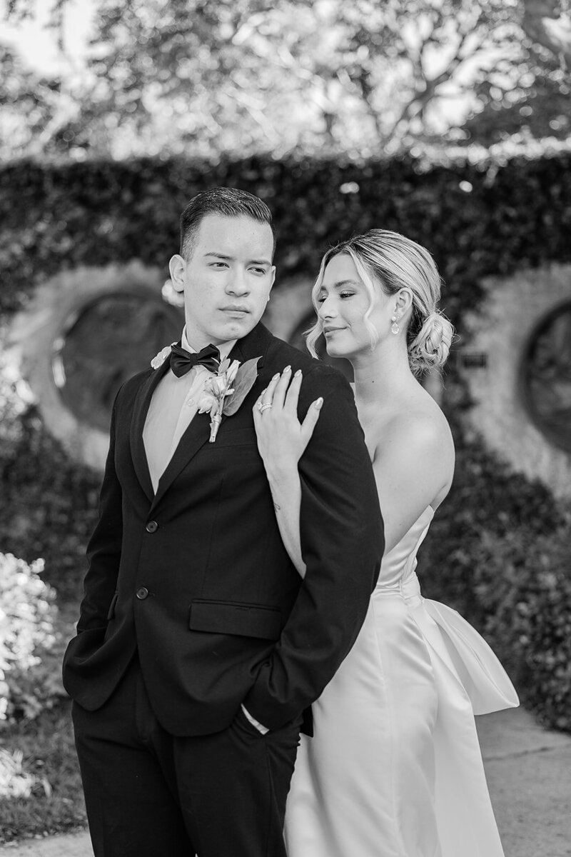Bride and groom located in a wedding venue in Winter Park Fl  holding each other for their portraits in from of a hedge wall.