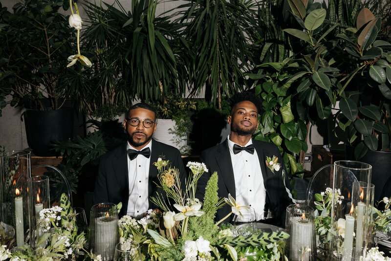 Gay grooms sitting at the head table at their wedding Q Jancola