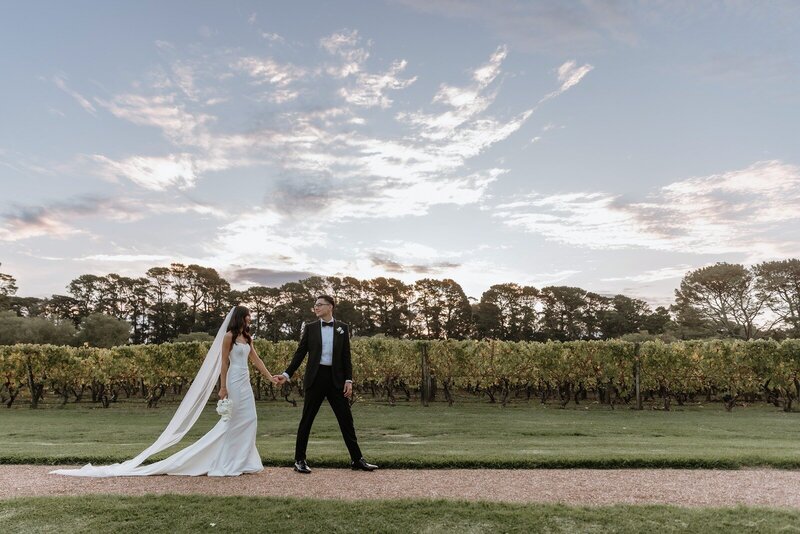 A couple who have just gotten married walking along a garden path with a beautiful sky