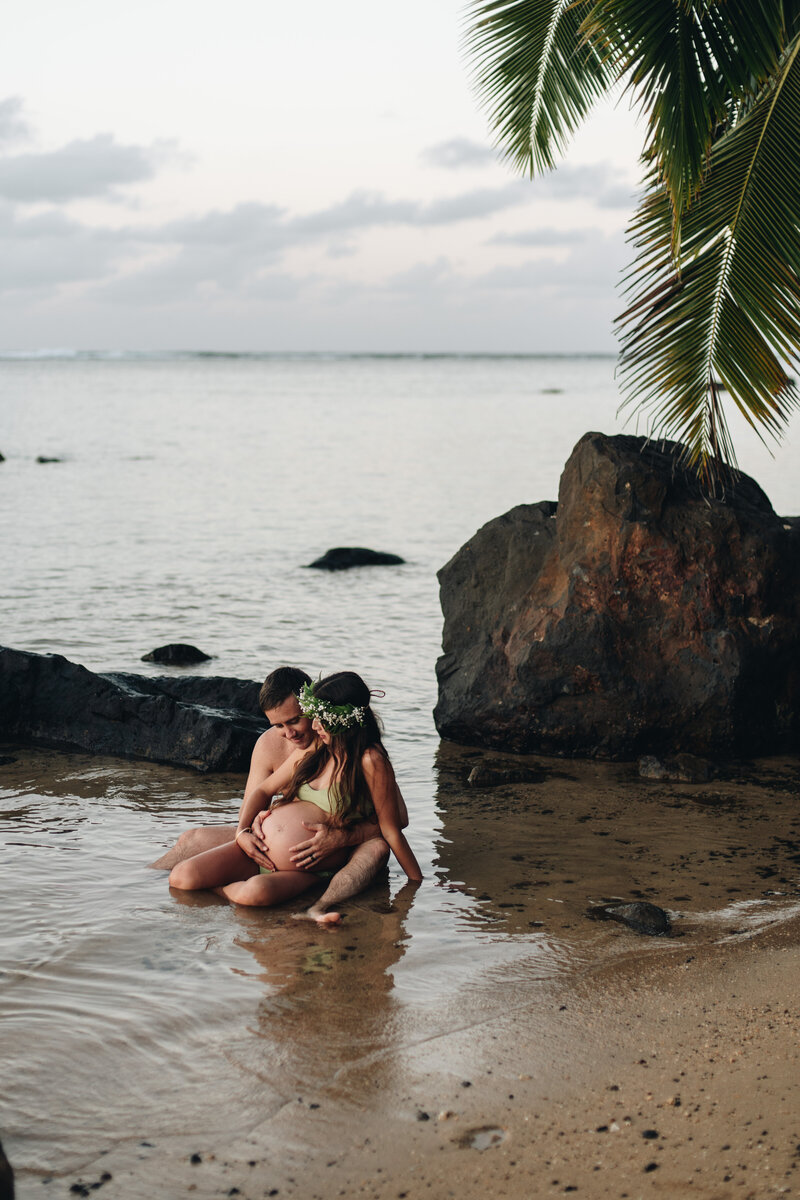 Couple who are pregnant sitting in the water
