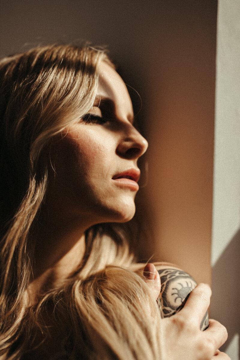 woman facing window with eyes closed