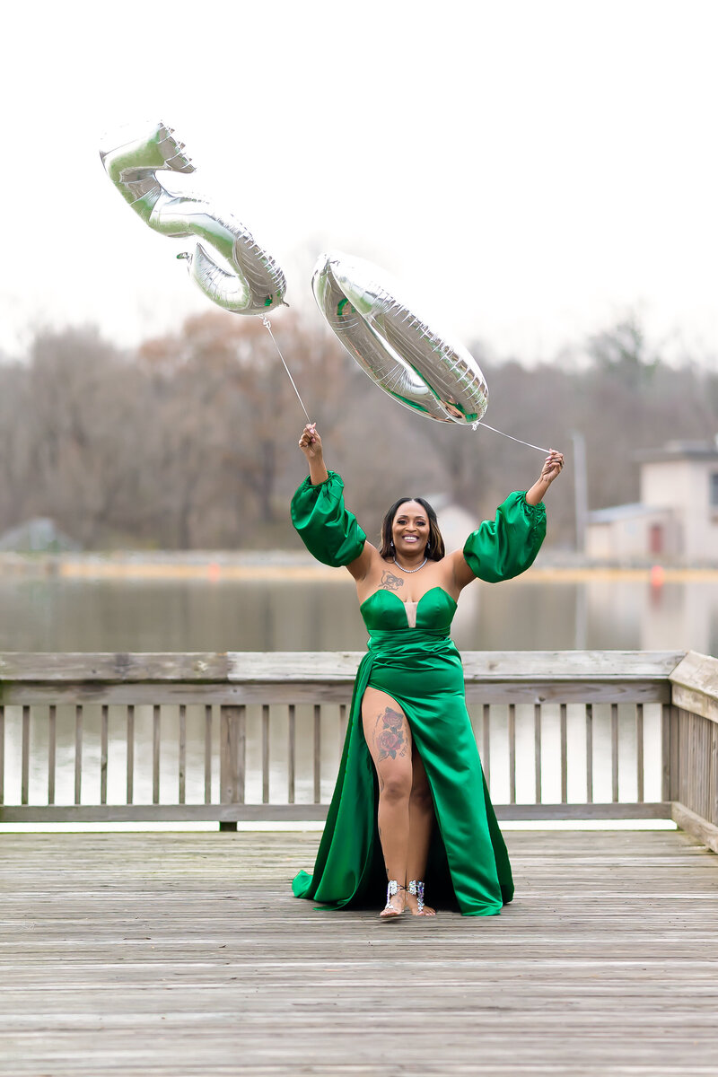 50th milestone birthday photoshoot woman wearing green ball gown by a lake