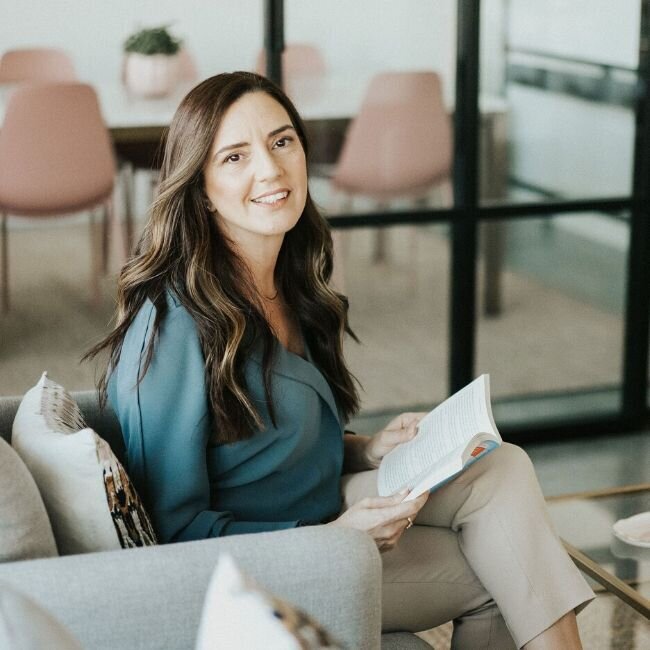 Idt Sharoni sits in her therapy office as she reads a book. Contact her therapy practice to get in touch with a marriage counselor in Florida. A Florida therapist can help you cultivate your relationship.