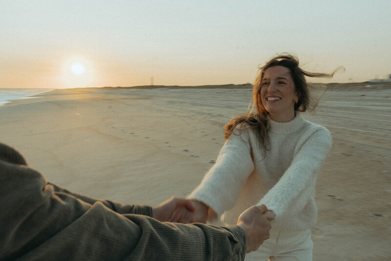 couple holding hands during beach engagement photos, captured by Elsie Goodman, an NYC engagement and couples photographer