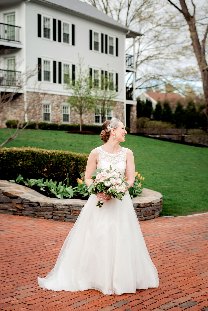 Bride holding her bouquet standing outside her wedding venue and laughing over her shoulder