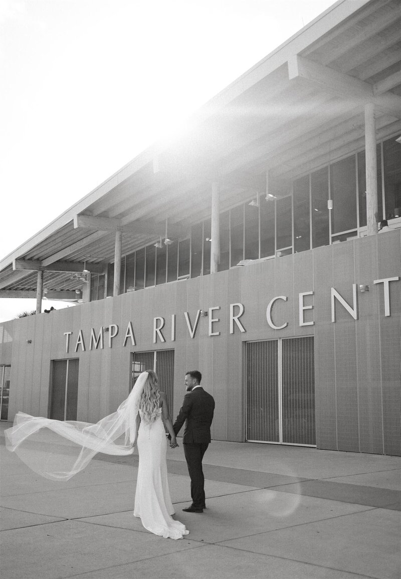 Black and white candid wedding photo of bride and groom walking away at Tampa River Center in Tampa FL
