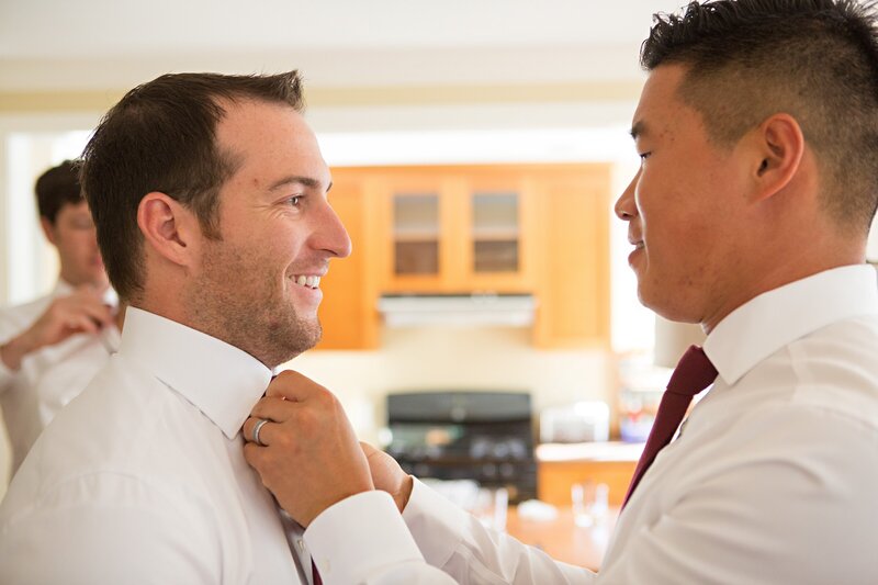 Groomsman adjusts the tie of the groom