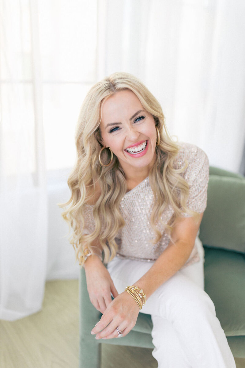 Woman in white pants and sparkly top smiles for camera