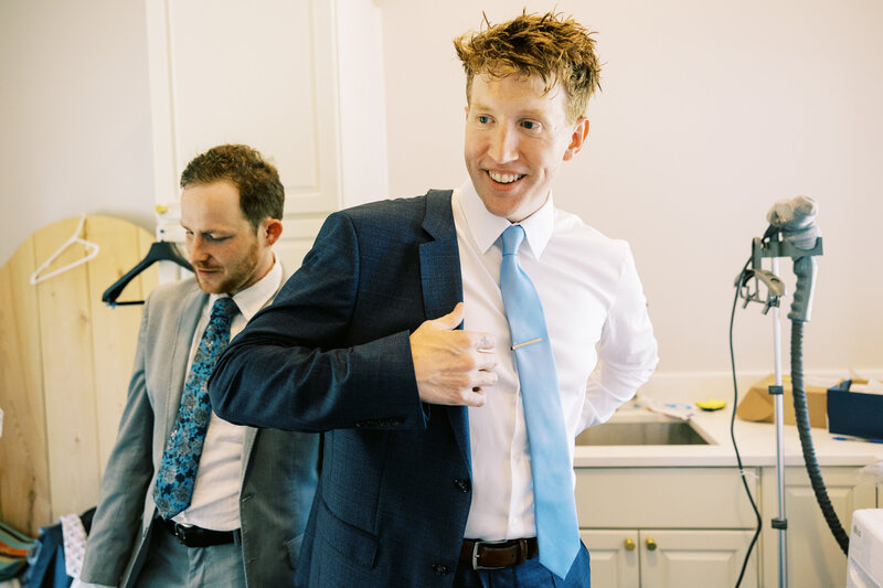 A candid moment from the joyful groom as he puts on his suit jacket in preparation of this wedding day.