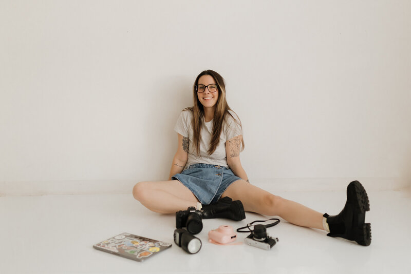 photo of a langley family photographer sitting on the ground and smiling at the camera with her gear around her on the floor