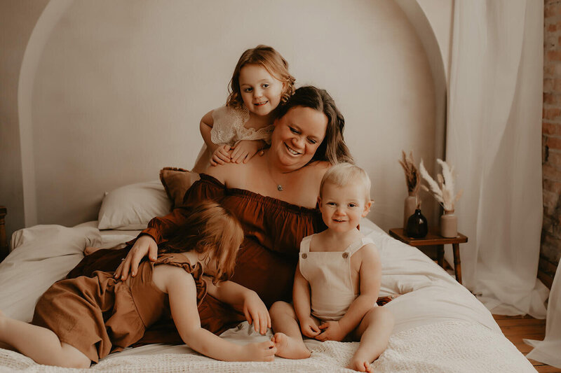 An expectant mother laying on a bed surrounded by her children
