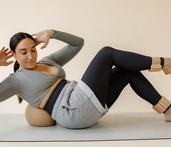 Female fitness and barre instructor doing a core workout on the ground. 