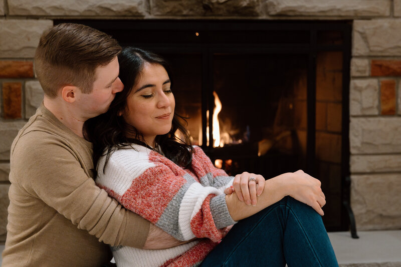 Couple embracing in front of a fire.