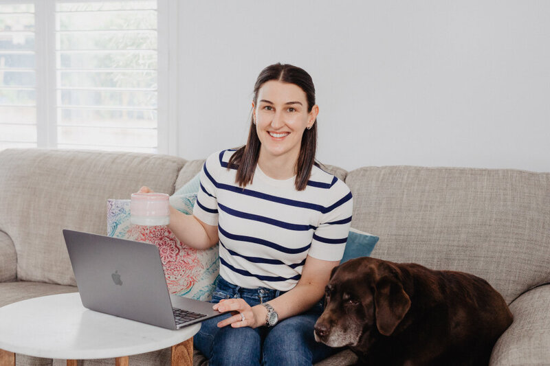 Nutritionist sitting on couch drinking tea with brown dog