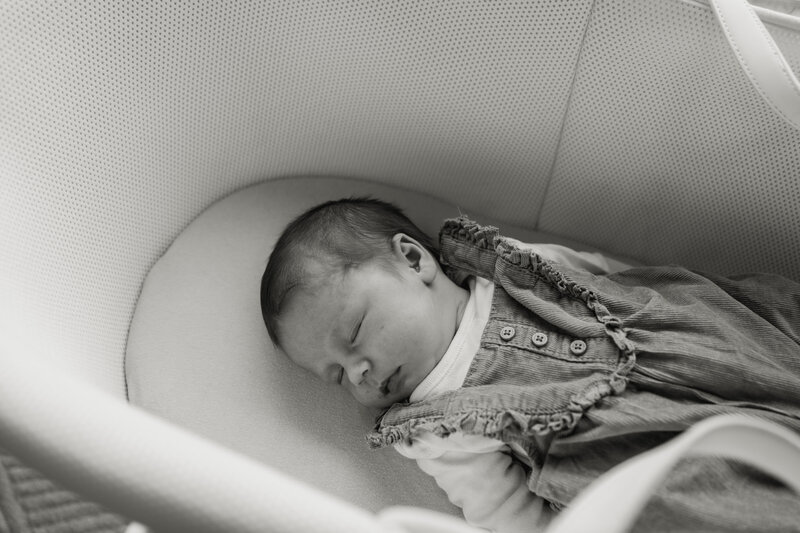 A newborn baby sleeping soundly in a bassinet during a relaxed, at-home lifestyle session in Nottingham. Captured in soft natural light to reflect the quiet beauty of early days.