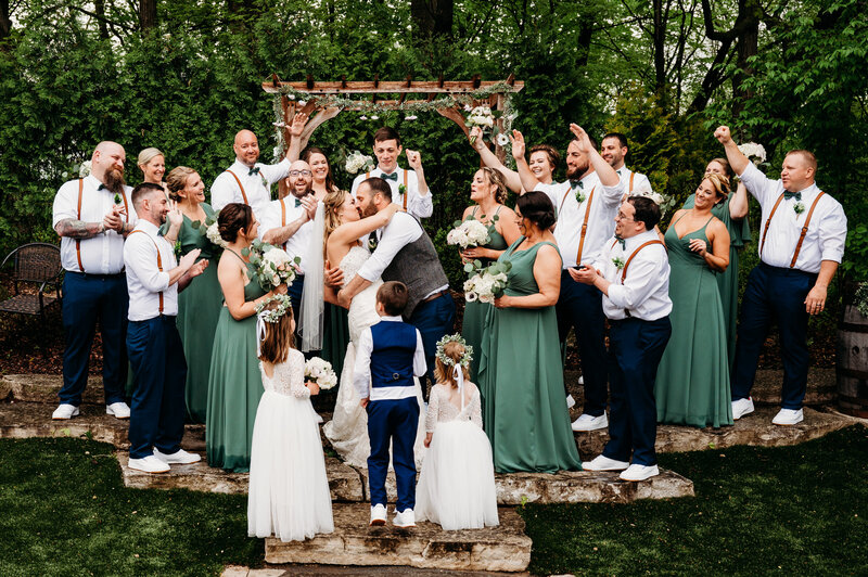 Bride and groom kissing while their bridal party cheers