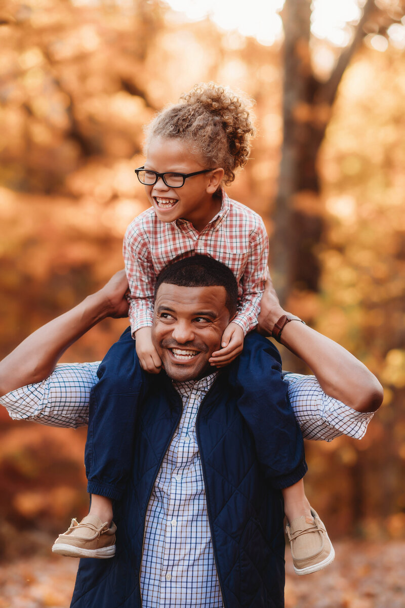 Father holds his son atop his shoulders during Fall Family Photos on the Blue Ridge Parkway in Asheville, NC.