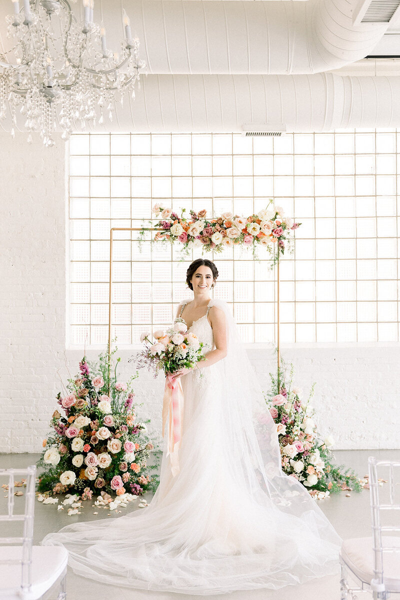bride in front of floral arbor