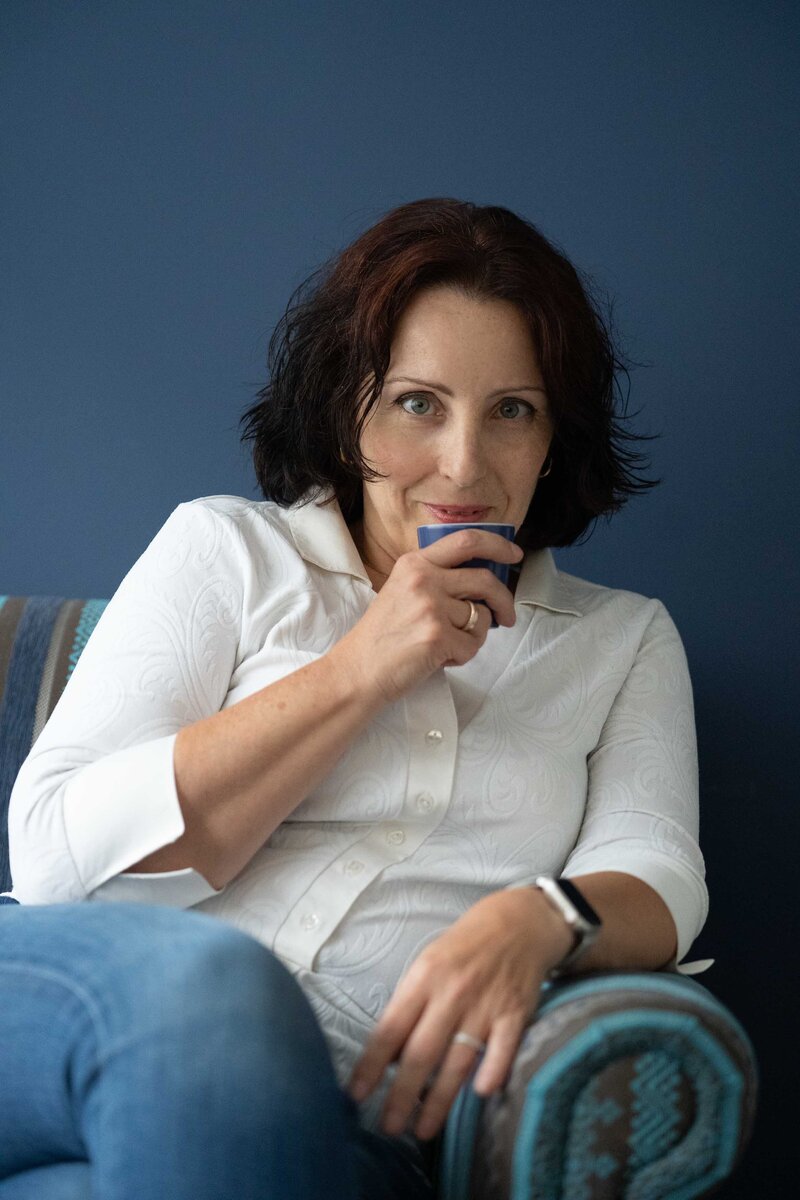 Csilla with a slight smile, looking at us over a cup of coffee.