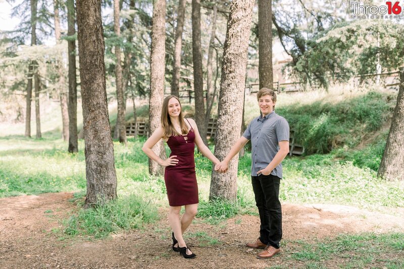 Engaged couple hold hands and smile for the wedding photographer