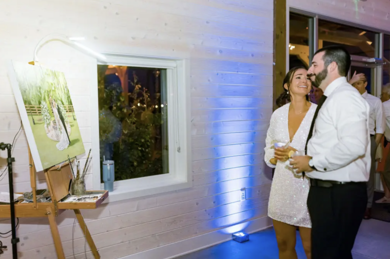 bride and groom look at painting