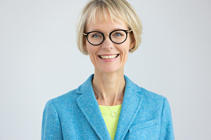 Welcoming Headshot of Woman with glasses and blue jacket
