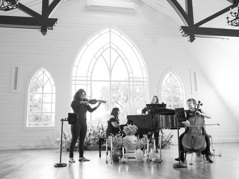 Mikaela Kahn playing live wedding music on a piano with an ensemble