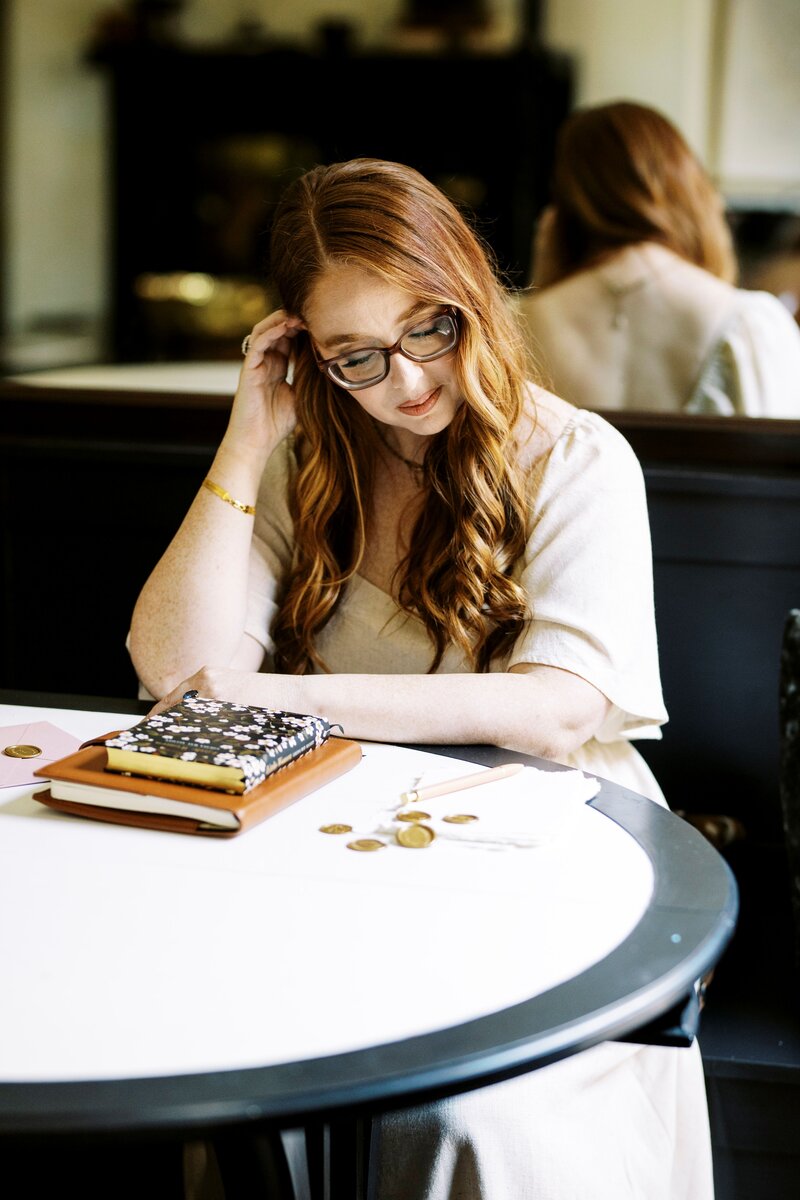 monica sitting at table and pushing hair back