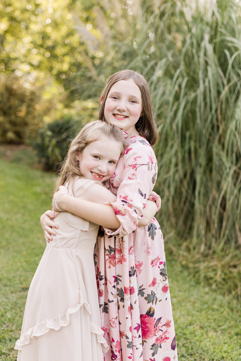 Sisters hug and smile outdoors