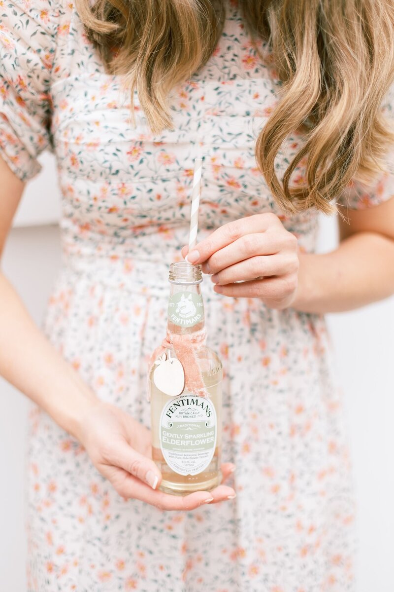Woman in floral dress holding cute pink soda with straw