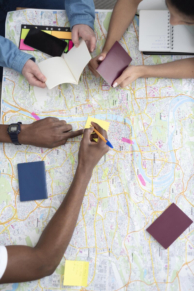 Hands planning a luxury adventure road trip on a detailed map, marking custom routes and accommodations with expert guidance for a seamless overland experience.