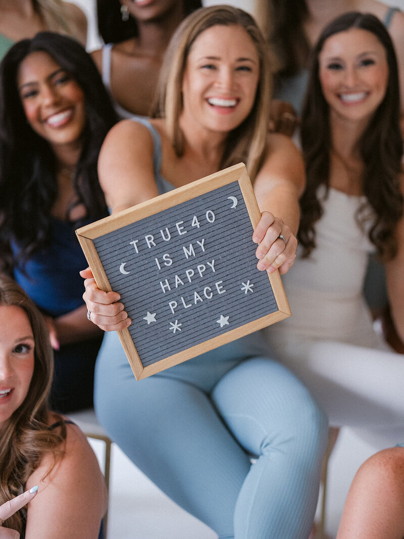 woman holding "true40 is my happy place" sign
