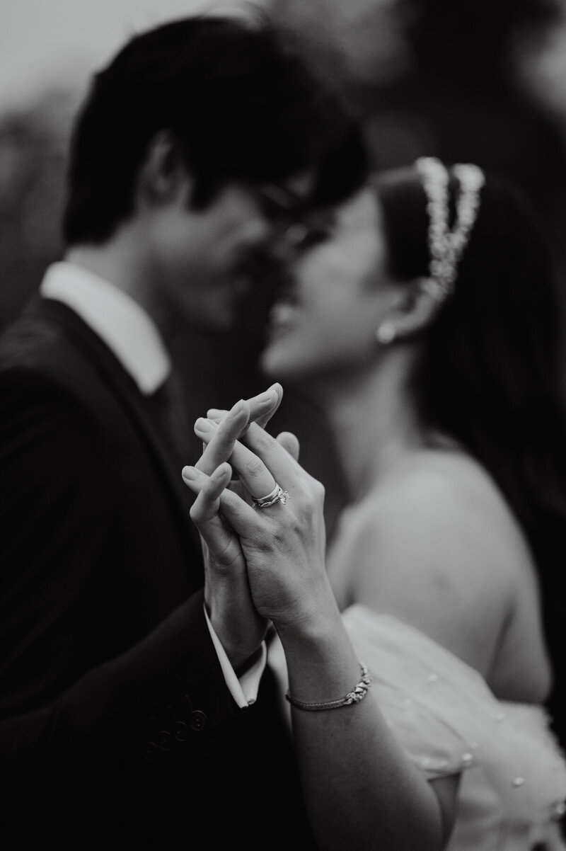 Close up of a couple dancing with their heads close together. Focus is on their hands and her engagement ring is featured prominantly 