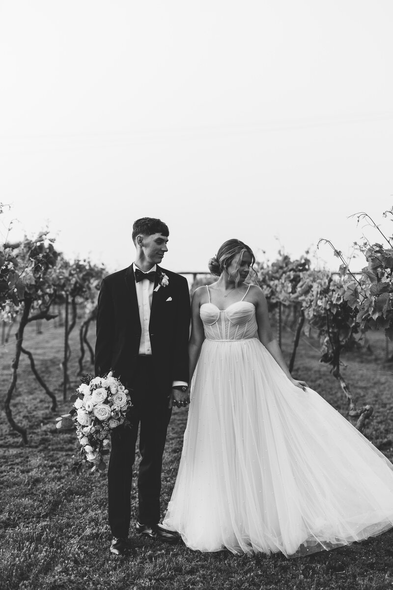 Bride and Groom holding hands between grape vines at Prairie Hill Vineyard Colwich, Kansas