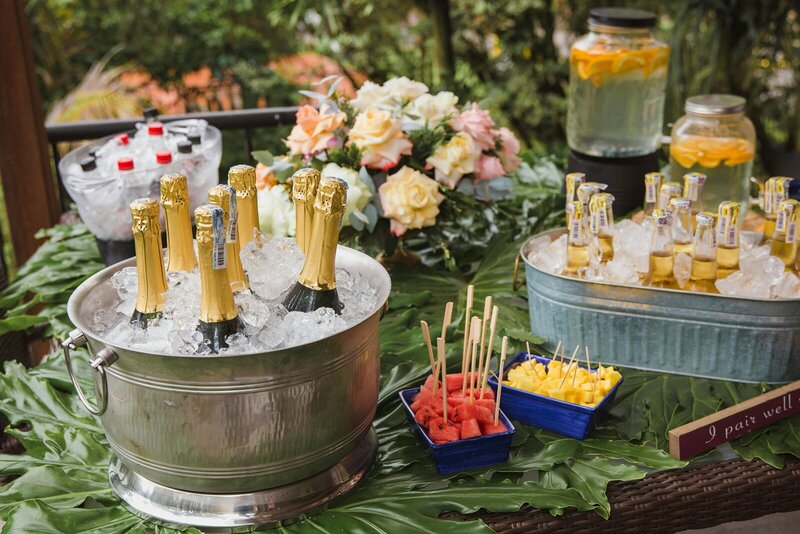 Outdoor drink station with champagne, mini drinks, and fruit skewers