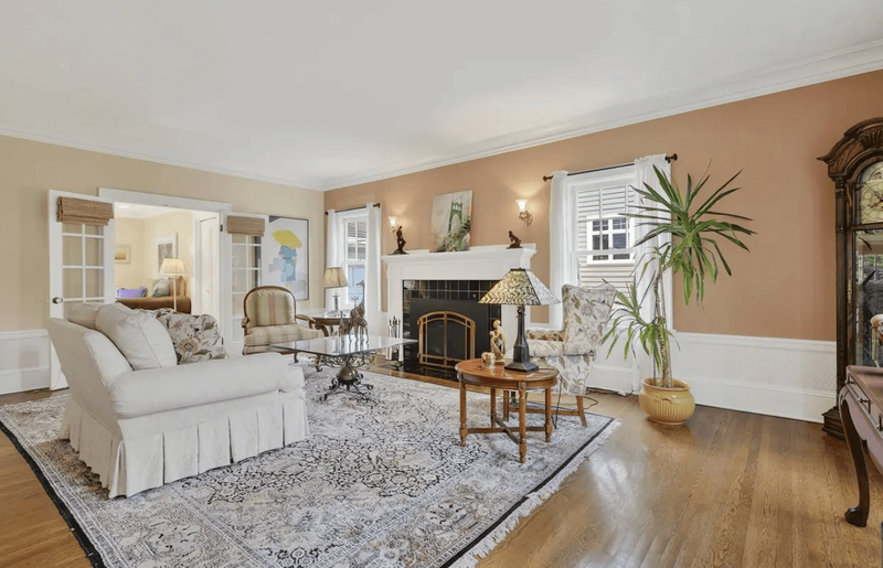 A living room featuring a fireplace and a large throw rug under the couch and chairs.