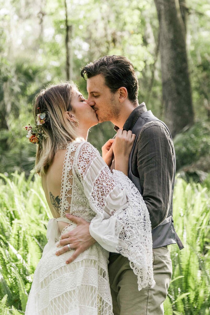 Bride and groom kissing in a field of ferns