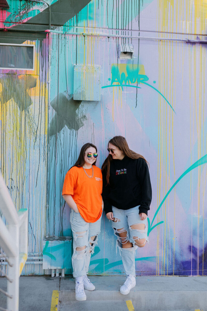 KP and Jessie leaning on a splatter paint wall