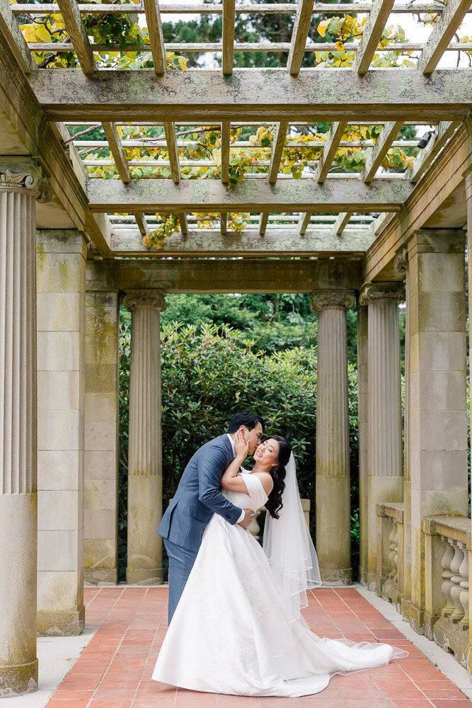 Wedding Photographer in Newport, RI, CT, and beyond | The Corteses | Groom kissing Bride on the cheek in a garden.