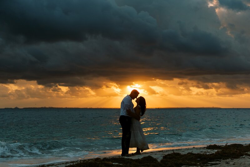 a couple sharing a romantic gesture under the sunset by the beach in cancun a wedding destination planned by sunberry travel co