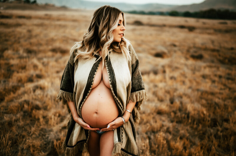 Pregnant mother in a parka holding her belly .