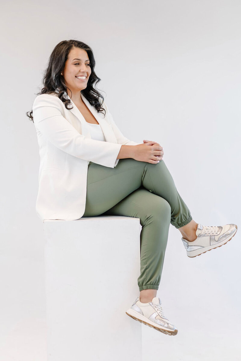 Woman with dark hair and a white blazer smiling