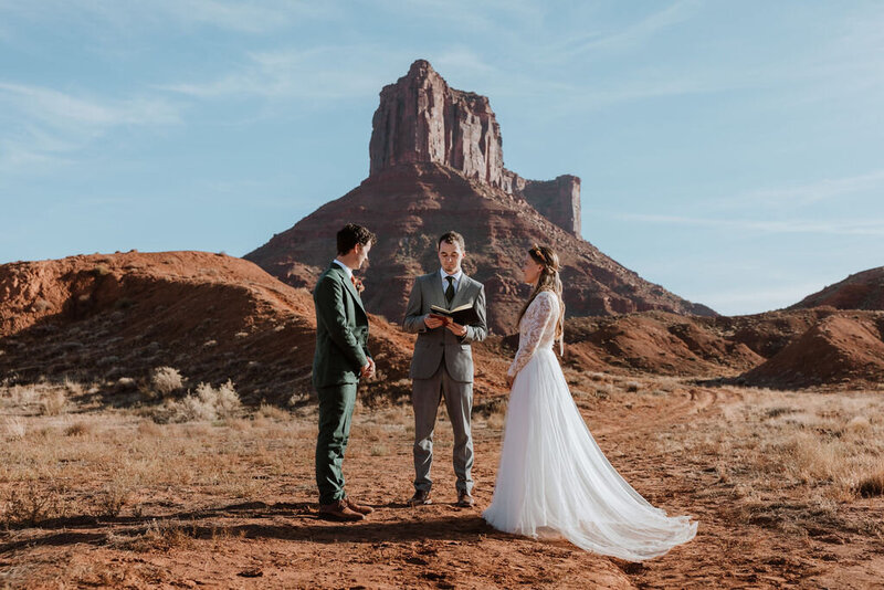 bride and groom standing with their efficient in the desert