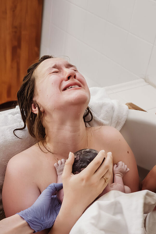 mother cries after birth holding her newborn